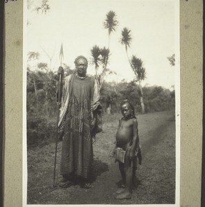 Notable Bali man with his small servant, who has to carry everything for him, 1928