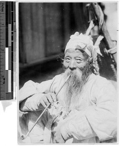 Elderly Korean man with long beard smoking a pipe, Korea, ca. 1920-1940