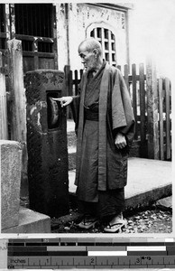 Japanese man spinning the prayer wheel, Japan, August 1932