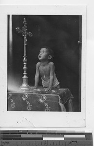 A small boy looking up at the crucifix in China, 1941