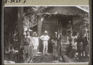 In front of a Dayak hut: Rev. Walter with natives, in the doorway Rev. & Mrs Braun