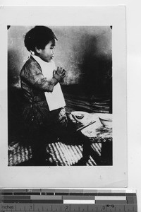 A child prays before a meal at Fushun, China