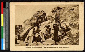 Priest standing with workers before a rock face, South Africa, ca.1920-1940