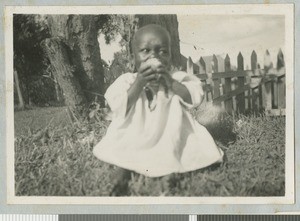 Infant eating fruit, Chogoria, Kenya, ca.1940