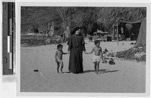 Sr. Marcus Marie, MM, walking with two children on the beach, Waianae, Hawaii, November 1948