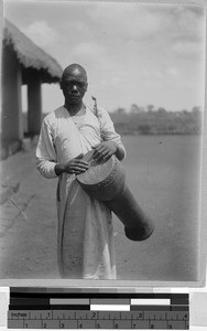 Man standing outside playing a drum, Africa, ca. 1920-1940