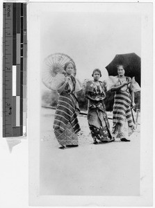 Three Filipinas in traditional dress standing on a road, Philippines, ca. 1920-1940