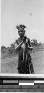 Boy standing outside holding a bow and arrow, Africa, August 1948