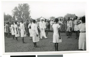 Resident commissioner walking through a row of schoolchildren at the coronation celebration, Ramotswa, Botswana, 1937