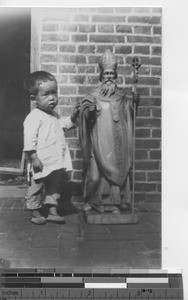 A child with a statue of St. Patrick at Fushun, China, 1934