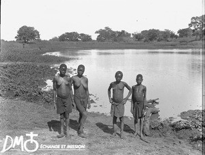 African girls standing on the shore of a little lake, Antioka, Mozambique, ca. 1896-1911