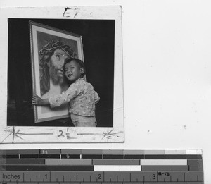 A young boy embracing a painting of Jesus in China, 1941