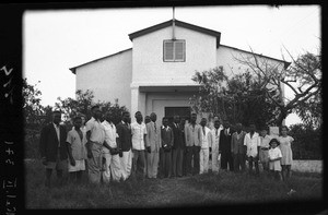 African men and people of European origin standing in front of a former movie theater used as a place of worship, Beira, Mozambique, 1947