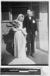 Bride and groom standing in front of a brick building, Korea, 1949
