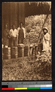 Missionary father standing with workmen outside a brick building, Congo, ca.1920-1940