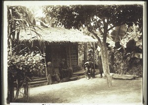 African hut in Bodiman. In front are two women peeling Makabo (1928)