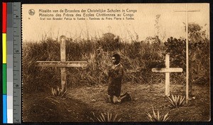 Man kneels in prayer next to two grave sites, Congo, ca.1920-1940