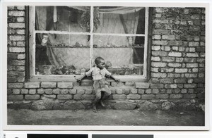 Child sitting in front of the shop window of a witchdoctor, Krugersdorp, South Africa