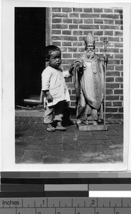 Young child stands next to statue, Yeung Kong, China, ca. 1930