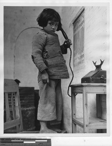 A young girl using a telephone at Cenqi, China, 1948