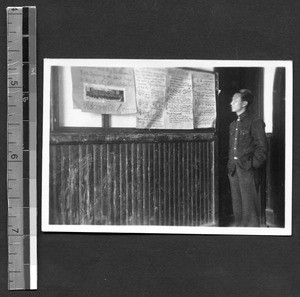 Fukien Christian University student looking a poster and music, Shaowu, Fujian, China, 1938