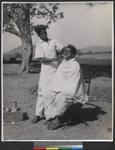 Leper shaving a fellow patient outdoors, India, ca.1919-1943