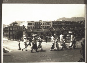 Chinese funeral in Kowloon. Photograph by Rev. Weickum, Fopin. Children in mourning follow the coffin. In one hand they carry a stick to suport themselves, on the other side is someone leading them along