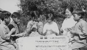 Blind Home in Mukden. An adult blind teaches the younger children in sewing. Applied 1935