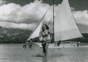 A young Tahitian woman in front of a outrigger canoe, Moorea