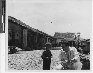 Fr. James Buttino with a child at Wuzhou, China, 1949