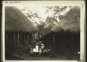 Elisa Ndifon's houses. The house on the left is inhabited by Elisa, the house on the right his wife Anna Binsen with two children and Elisa's mother, Sara, who is also a Christian. The people on the photographs are (l-r) Mrs Steudle with her Theophil, Mrs Schneider with Emmanuel Steudle, Mrs Elisa Ndifon with her Miriam (who died in the autumn of 1932)