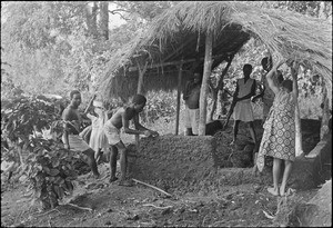 Pupils building the wall of a hut