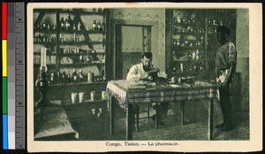 Missionary father using a microscope in a pharmacy, Congo, ca.1920-1940