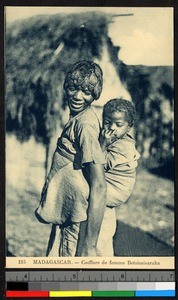 Young woman with plaited hair carrying infant, Madagascar, ca.1920-1940