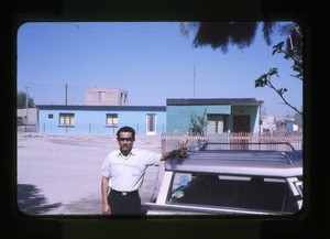 man beside a house and automobile