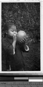 Girl blowing up a balloon, Loting, China, ca. 1930