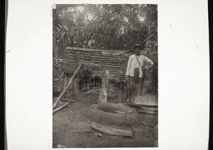 A hole for storing palm-oil. In the background a chicken-house