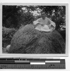 Fr. Dietz sitting atop a large pile of hay in Haiyan, China, 1925