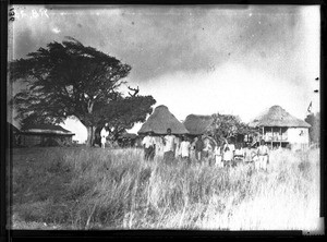 African people standing in front of buildings with thatched roofs, Mozambique