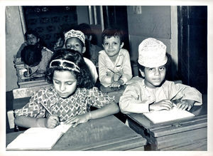 1. klasse i skolen i Muscat. Drengen på første række bærer den traditionelle omani-hat og kjortel. Kvasten i halsen er et sikkert tegn på, at kjortelen er syet i Oman. 19781st grade at the school in Muscat. The boy in the first row is wearing the traditional Omani cap and robe. The tassel at the neck is a sure sign that the robe was made in Oman. 1978