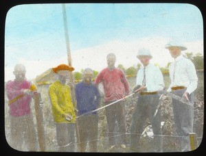 Missionaries and other men standing outdoors in a field, ca.1917-1923