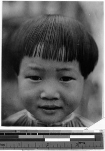 Smiling Japanese girl standing in front of a gate, Japan, ca. 1936