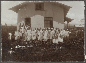 Crowd of people in front of a European style house, Tanzania