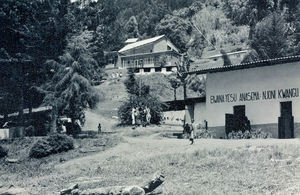 Fra Bumbuli Hospital, Tanzania. Lægemissionær Ernst A. Jacobsen fortæller: De pårørendes bolig i forgrunden med bibeltekst skrevet på muren, fra Matt. 11, 28. I baggrunden ses afdelingen for fysioterapi og bagved denne hospitalets kapel. (Ernst A. Jacobsen var læge ved hospitalet, 1966-70 og 1973-79)