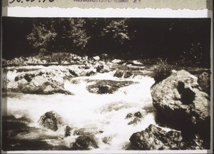 Eine Stromschnelle, bei der das leere Boot im Hintergund über hohe Felsen gezogen werden muss