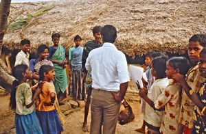 30.- Tamil Nadu, Indien, 1988-89. "Med 80 elever i klassen" - En dansk lærer i Arcot skoleprojekt fortæller: Eleverne skulle undersøge deres egen landsby ved først at indsamle en masse oplysninger i landsbyen. Det kunne dreje sig om husdyrhold, om religion, hvor deres længste rejse gik til, antal familiemedlemmer i huset, osv. Her hjælper Sundar dem i gang. Godt han var med helt fra starten, fordi landsbyen ved at se mig troede, de skulle svare på alle de spørgsmål for at få gratis ris og ragigrød. Sundar måtte så forklare, at det drejede sig om børnenes undervisning. Det forstod de godt og samarbejdede herefter fint med os ved at give alle de oplysninger, vi skulle bruge