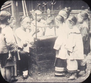 The "candy man" blowing animals out of colored molasses surrounded by children, Changde, Hunan, China, ca.1900-1919