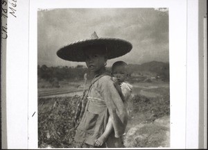 Chinese girl carrying her small brother on her back