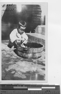 An orphan girl washing laundry at Luoding, China, 1929