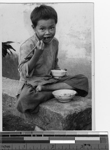 A young boy eating rice at Luoding, China, 1936